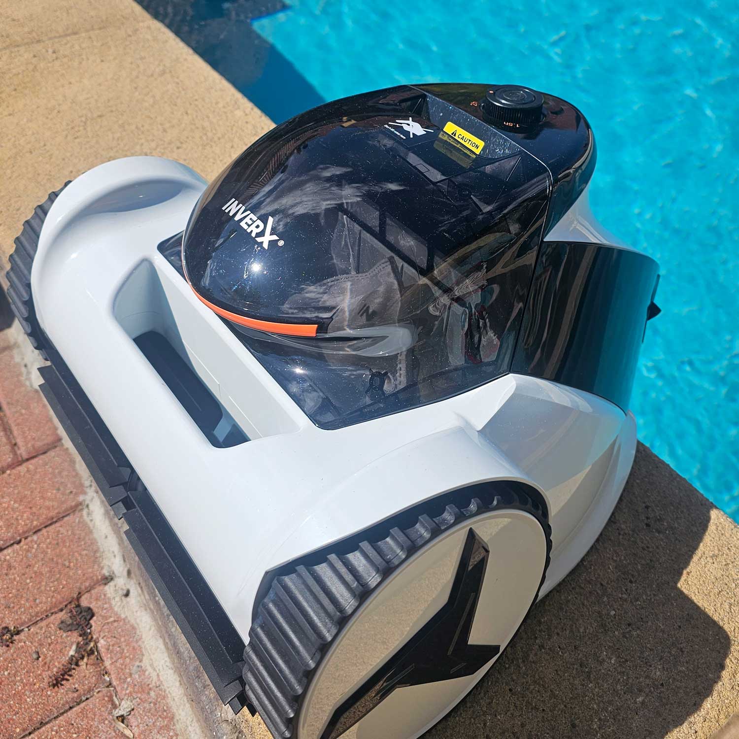 Automatischer Poolreiniger, der in der Nähe eines Schwimmbeckenrandes positioniert ist.
