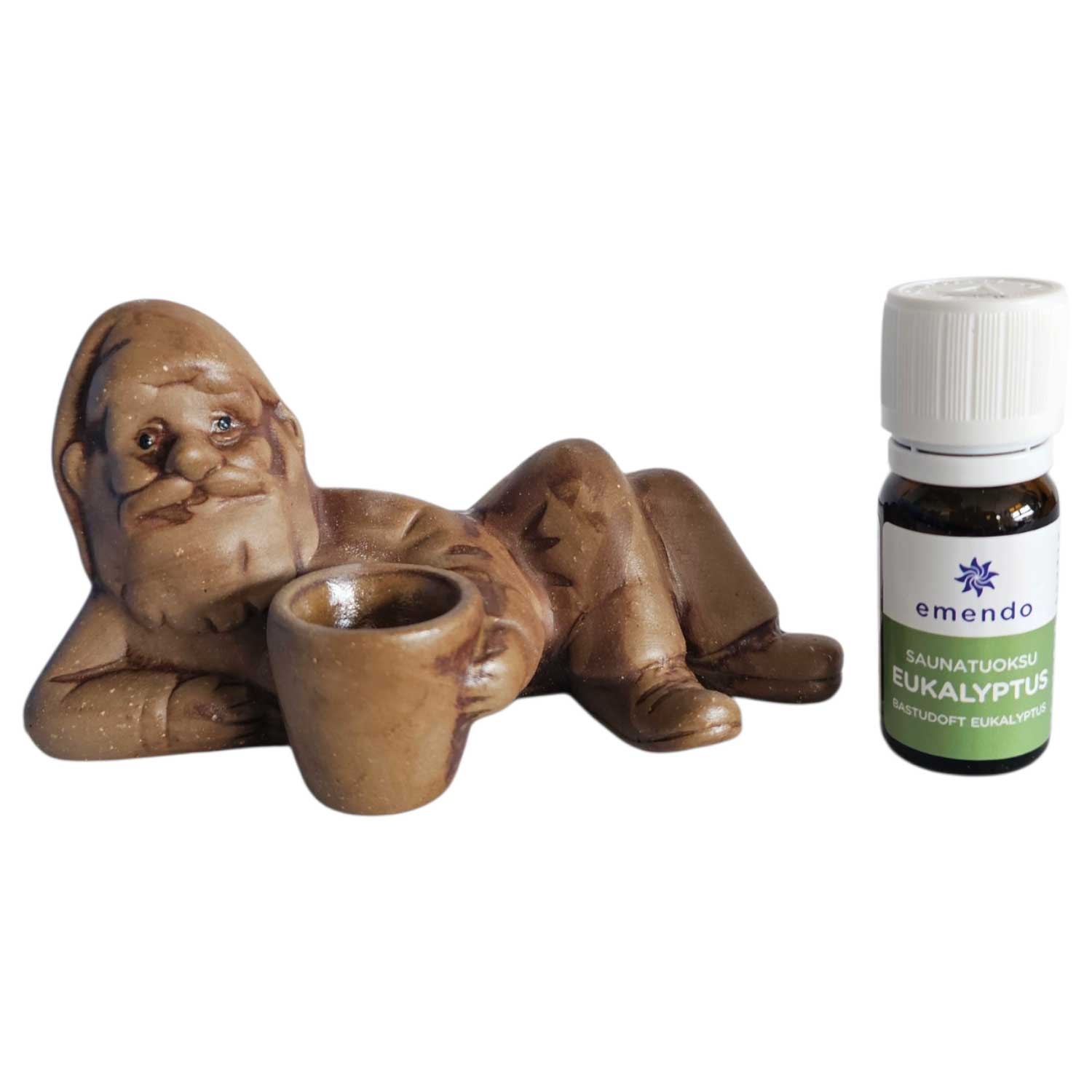 Eine Keramikzwergfigur, die neben einer kleinen Flasche Eukalyptus-Saunaduftöl liegt.