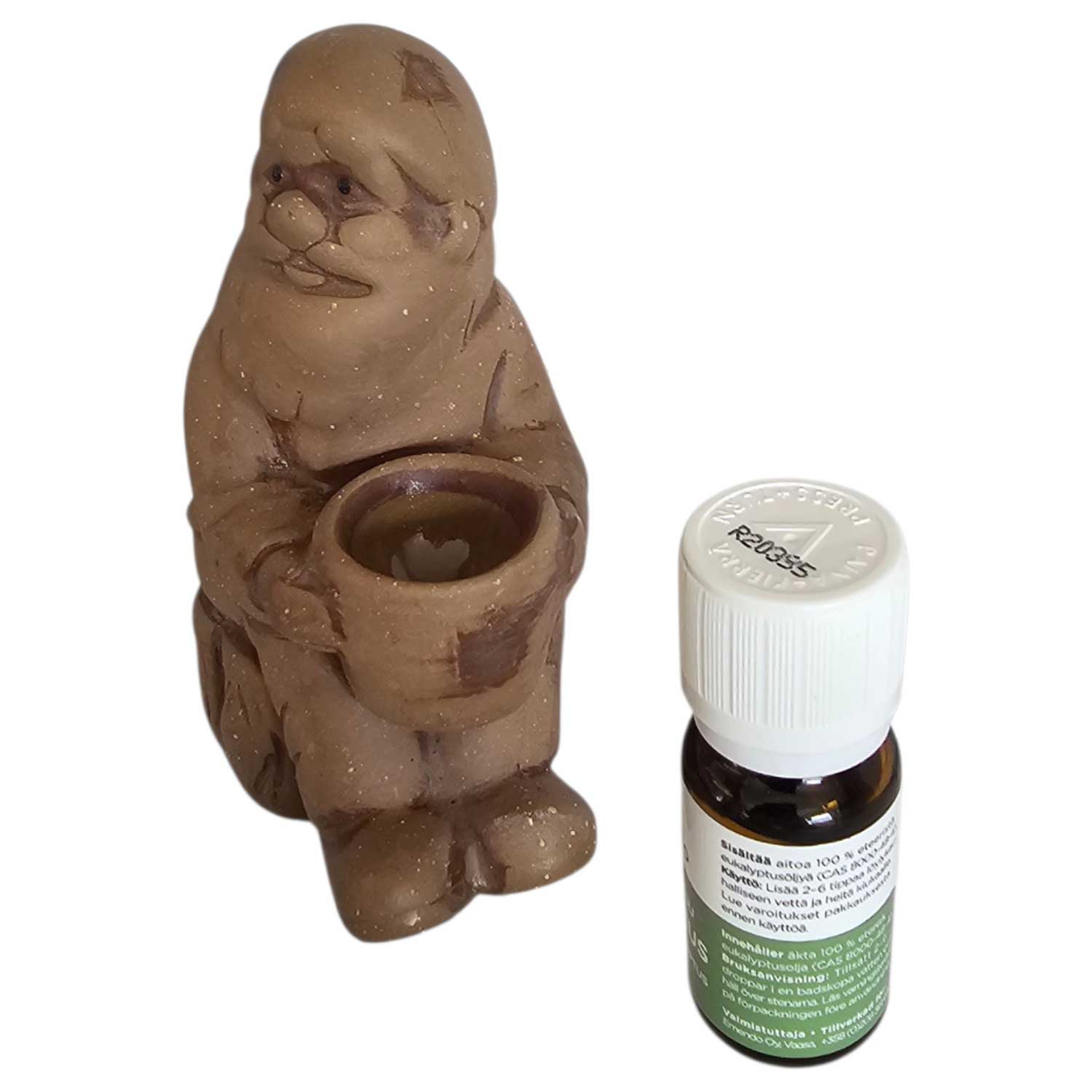 Eine kleine Keramikfigur eines sitzenden Mannes neben einer Flasche mit ätherischem Öl.