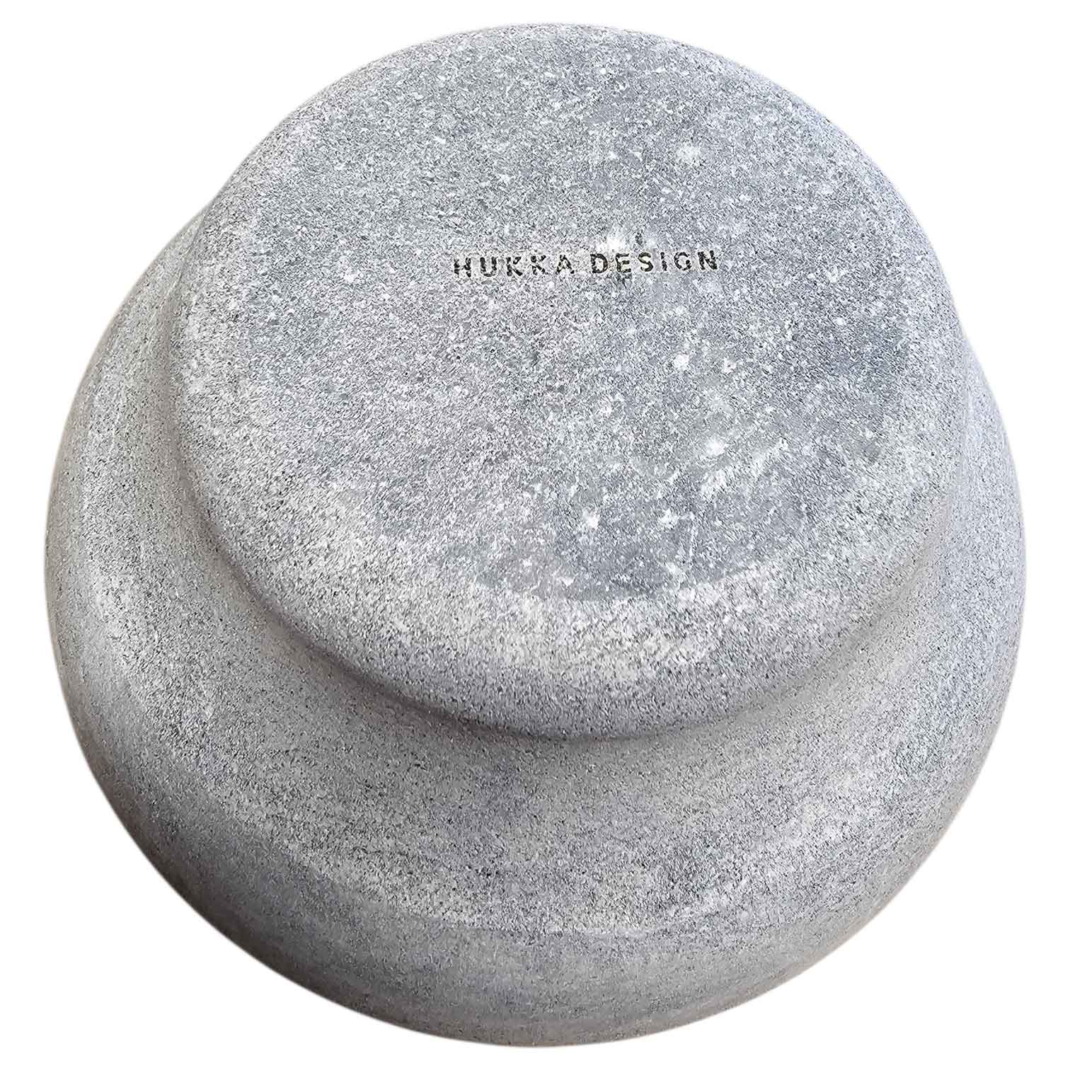 Ein Mörser- und Stößelset aus grauem, strukturiertem Stein, von oben betrachtet, mit der Gravur „HURKA DESIGN“.