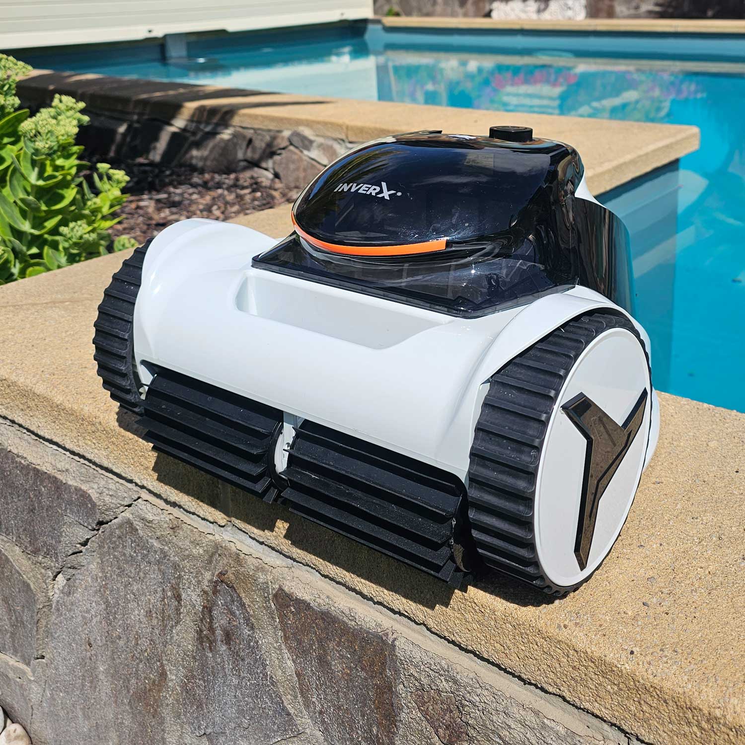 Automatischer Poolreiniger, der am Rand eines Schwimmbeckens positioniert ist.